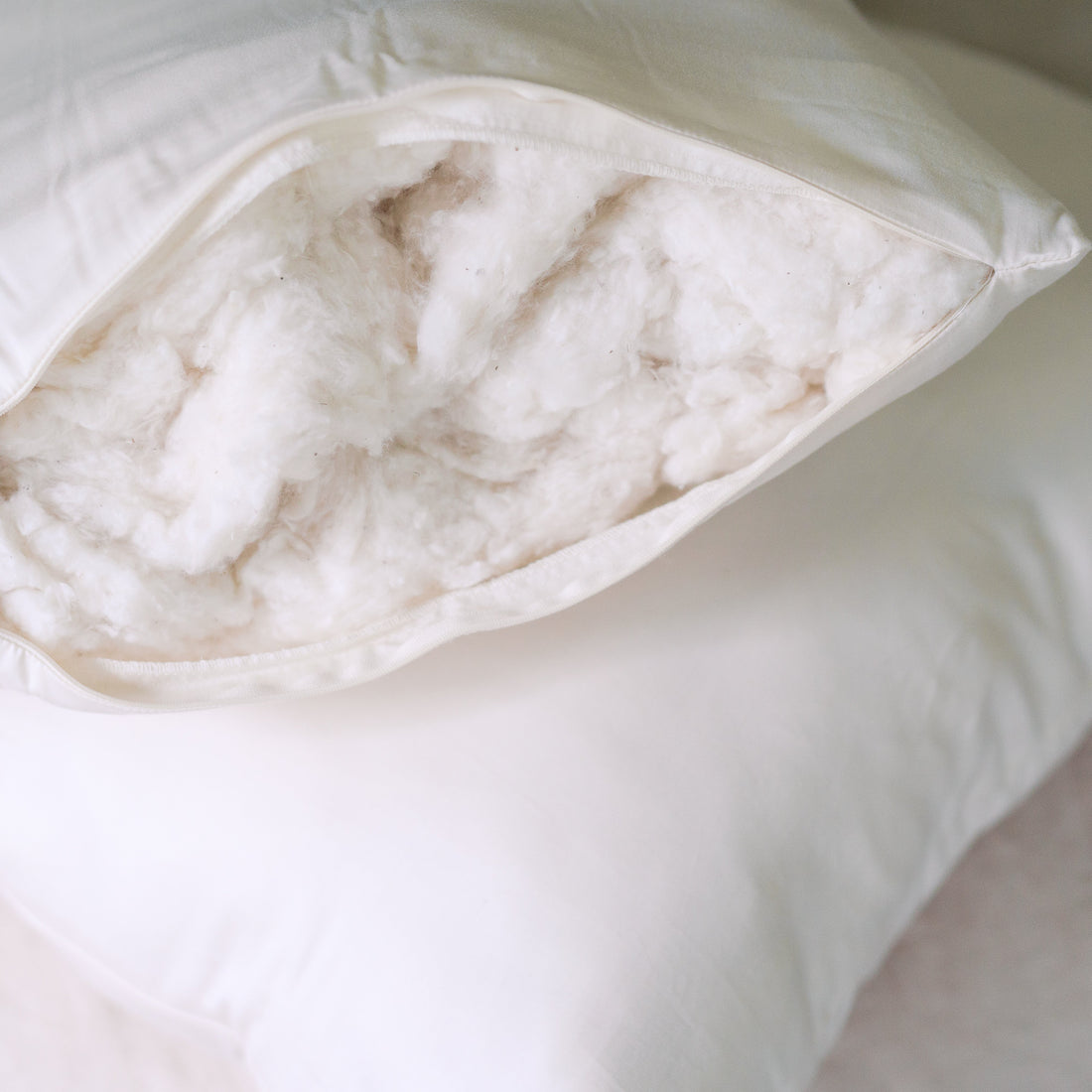 Close view of a Circadian Organic Cotton Pillow unzipped, showing the organic cotton inside the undyed organic cotton cover
