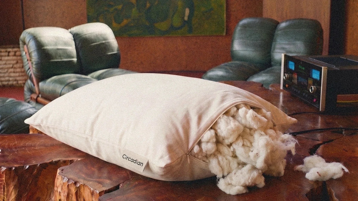 A Circadian Organic Cotton Pillow on a live-edge wooden table with its zipper open and organic cotton spilling out.