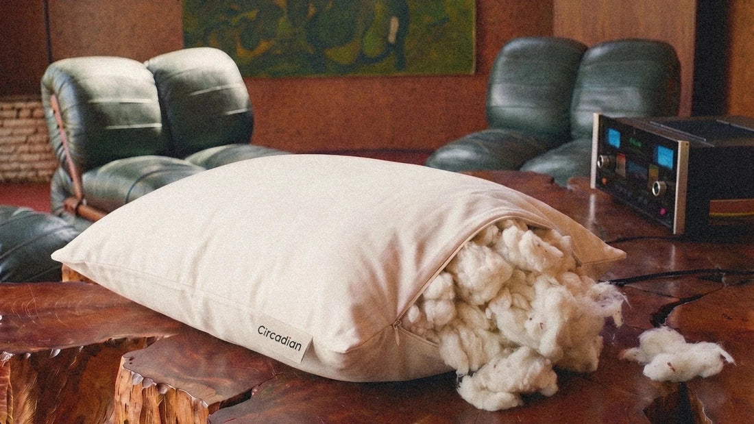 A Circadian Organic Cotton Pillow on a live-edge wooden table with its zipper open and organic cotton spilling out.