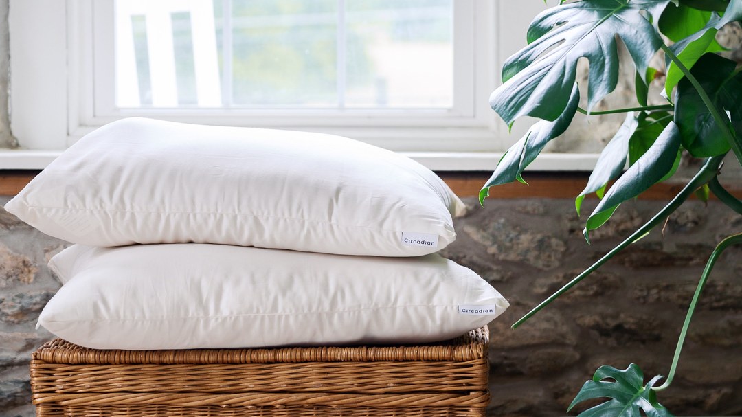 Two Organic Cotton Pillows stacked on a basket by a window