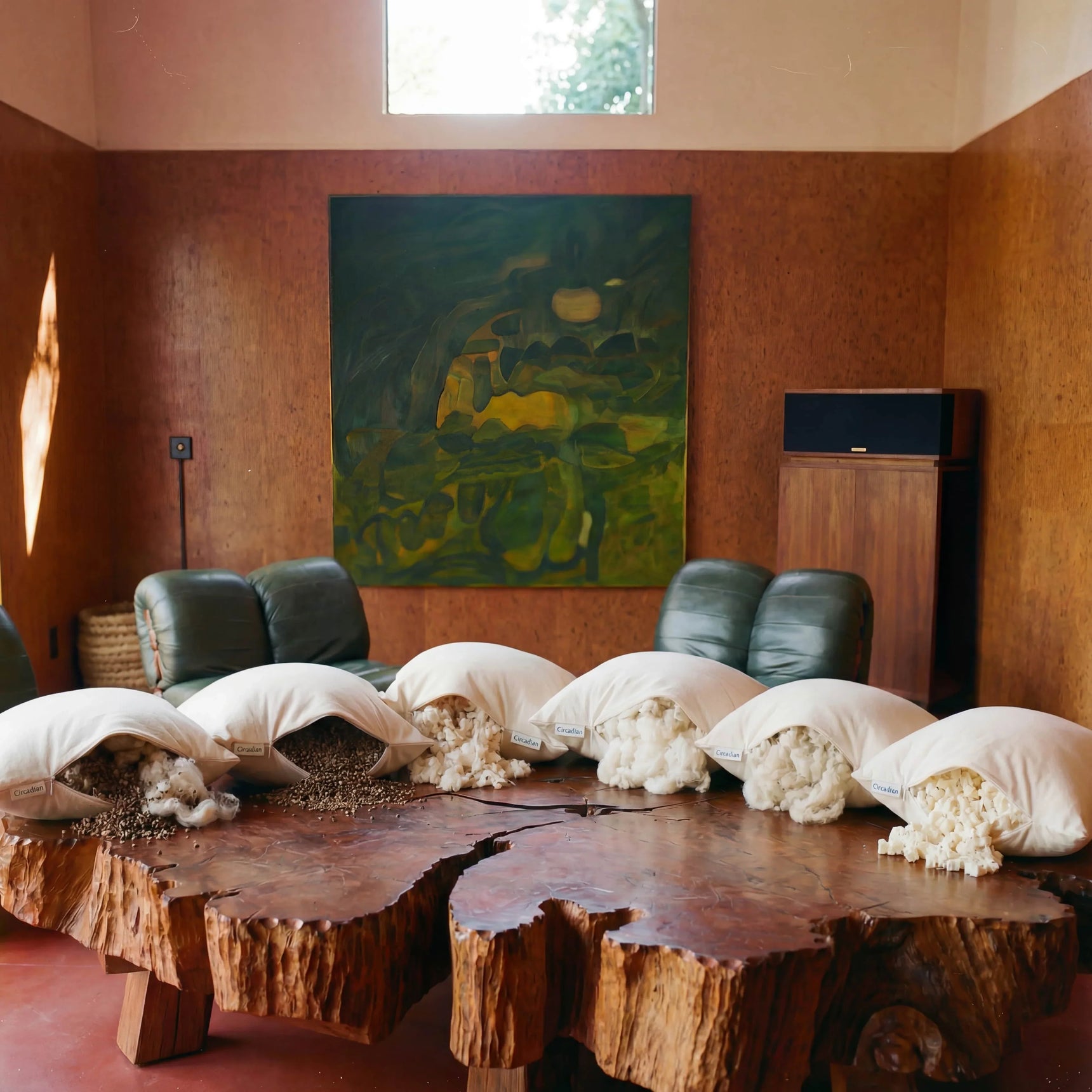 Six natural pillow fills - buckwheat, organic cotton, kapok, wool, latex, and buckwool hybrid - arranged on a wooden surface