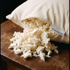 Shredded tree-tapped latex spilling from the open zipper of a Circadian dog bed onto a walnut table
