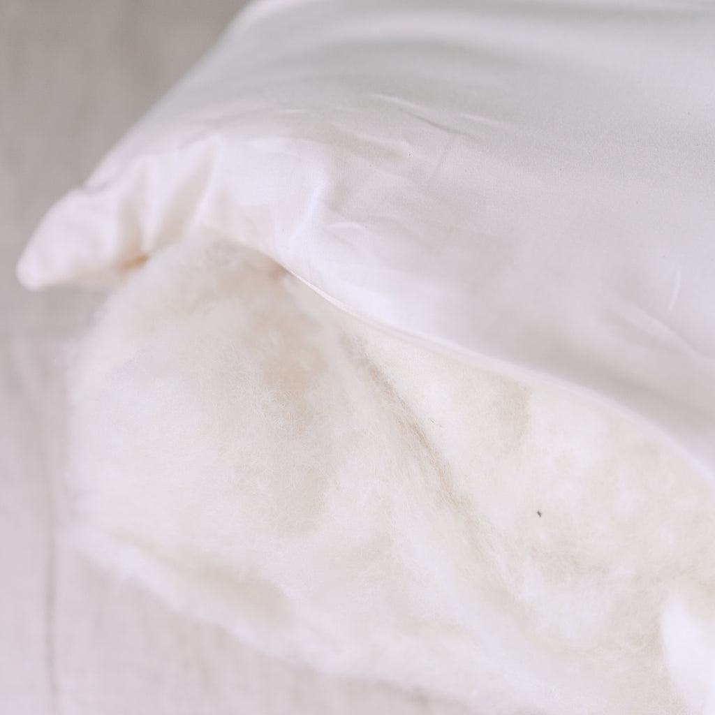 Organic wool fill visible through the open side zipper of a Circadian Organic Wool Pillow, showing the soft crimped wool batting inside.