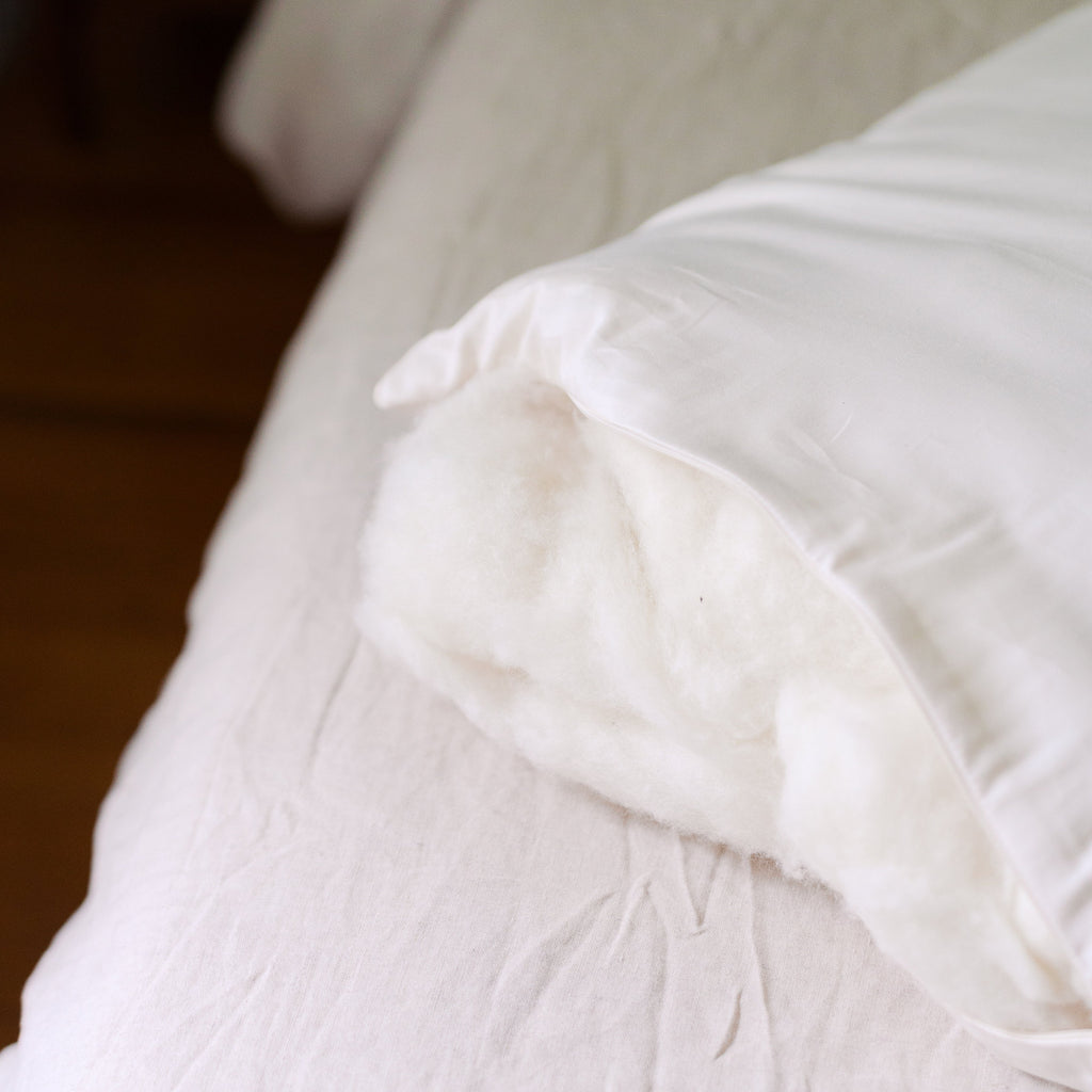 Rolled cross-section of the organic wool fill inside a Circadian Organic Wool Pillow, revealed through the side zipper.