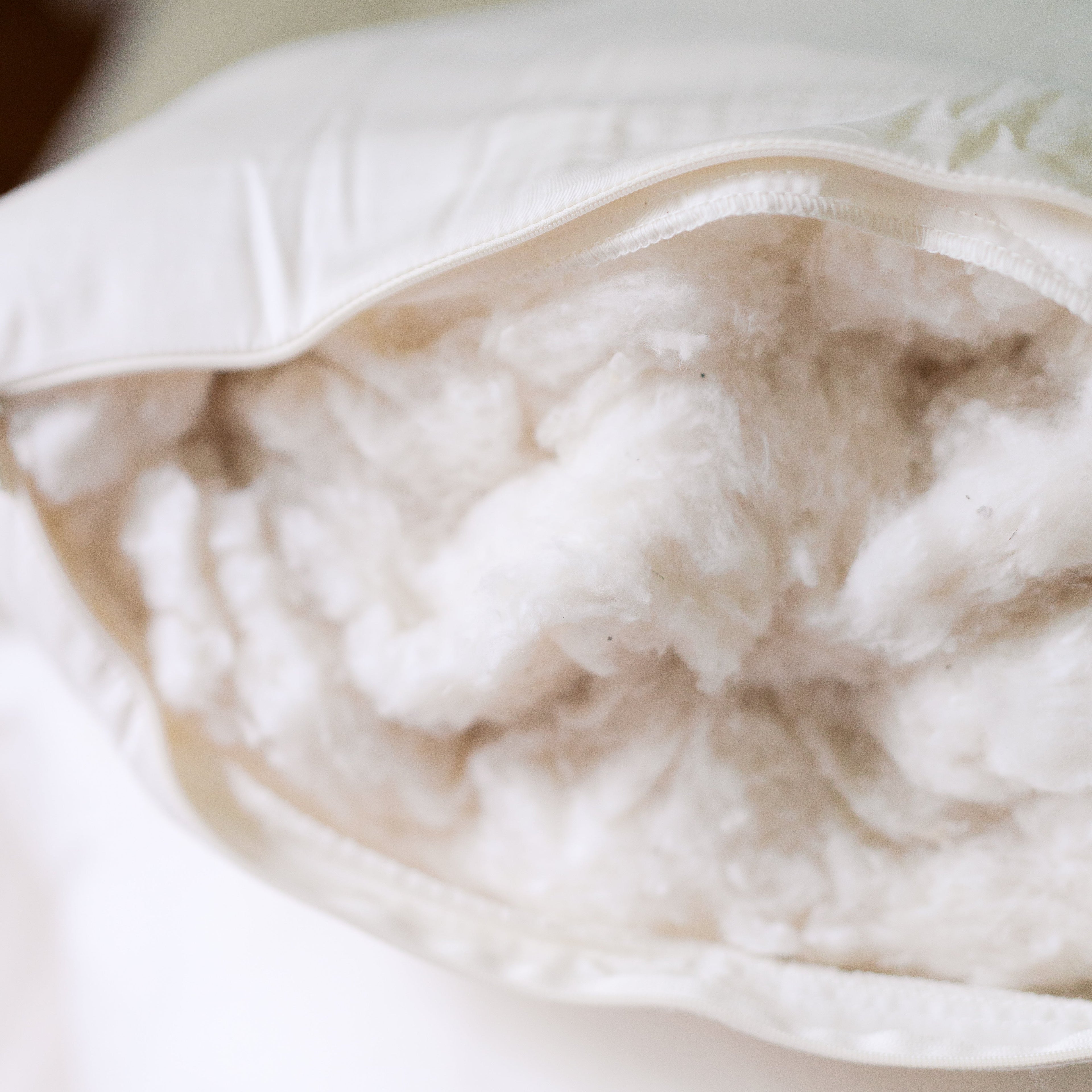 Organic cotton fill spilling from the open side zipper of a Circadian Organic Cotton Pillow, showing the soft natural cotton batting inside.