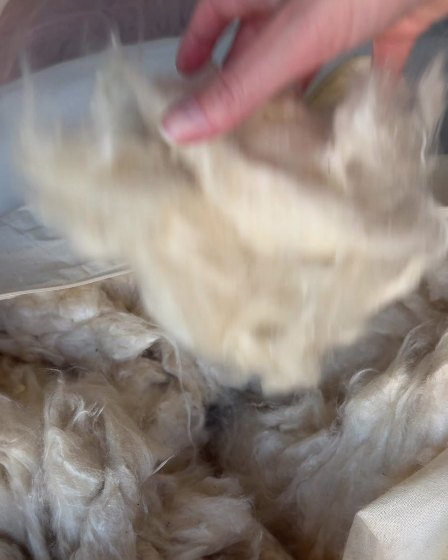 A hand lifting soft kapok inside a Circadian pillow