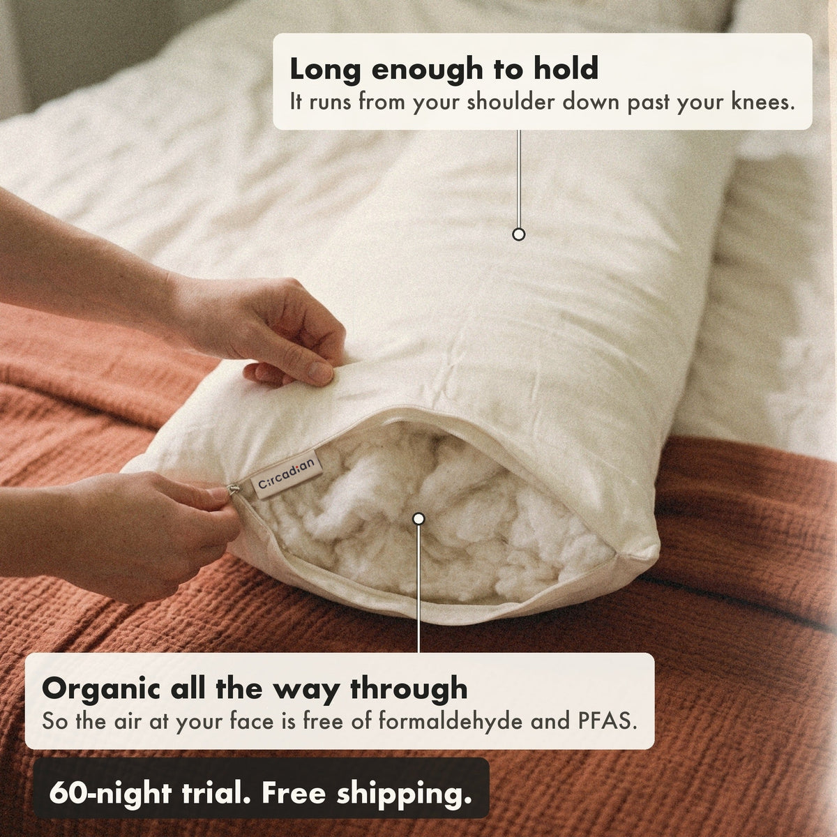 Hands open the zipper at the end of the Circadian Body Pillow to show the organic cotton inside, with labels: long enough to hold, from your shoulder down past your knees; organic all the way through, so the air at your face is free of formaldehyde and PFAS.