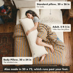Seen from above, a woman of 5 foot 5 sleeps on her side hugging the 20 by 54 inch Circadian Body Pillow on a queen bed, beside a standard 20 by 26 inch pillow; the pillow runs from her chin to her ankles and it also comes in 20 by 72.