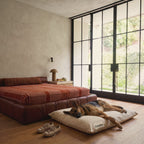 A German Shepherd stretched out asleep on the X-Large Circadian dog bed by tall garden windows.