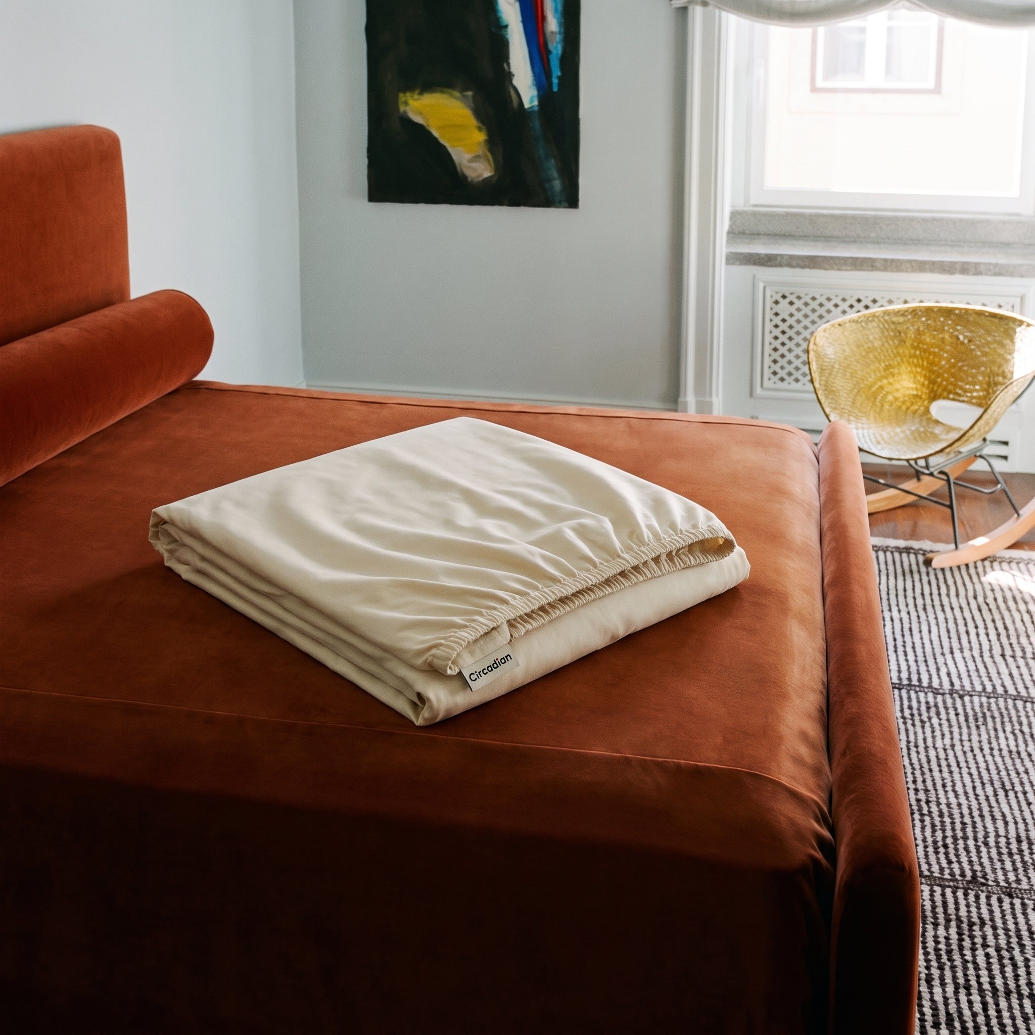 A folded organic cotton fitted sheet resting on a daybed