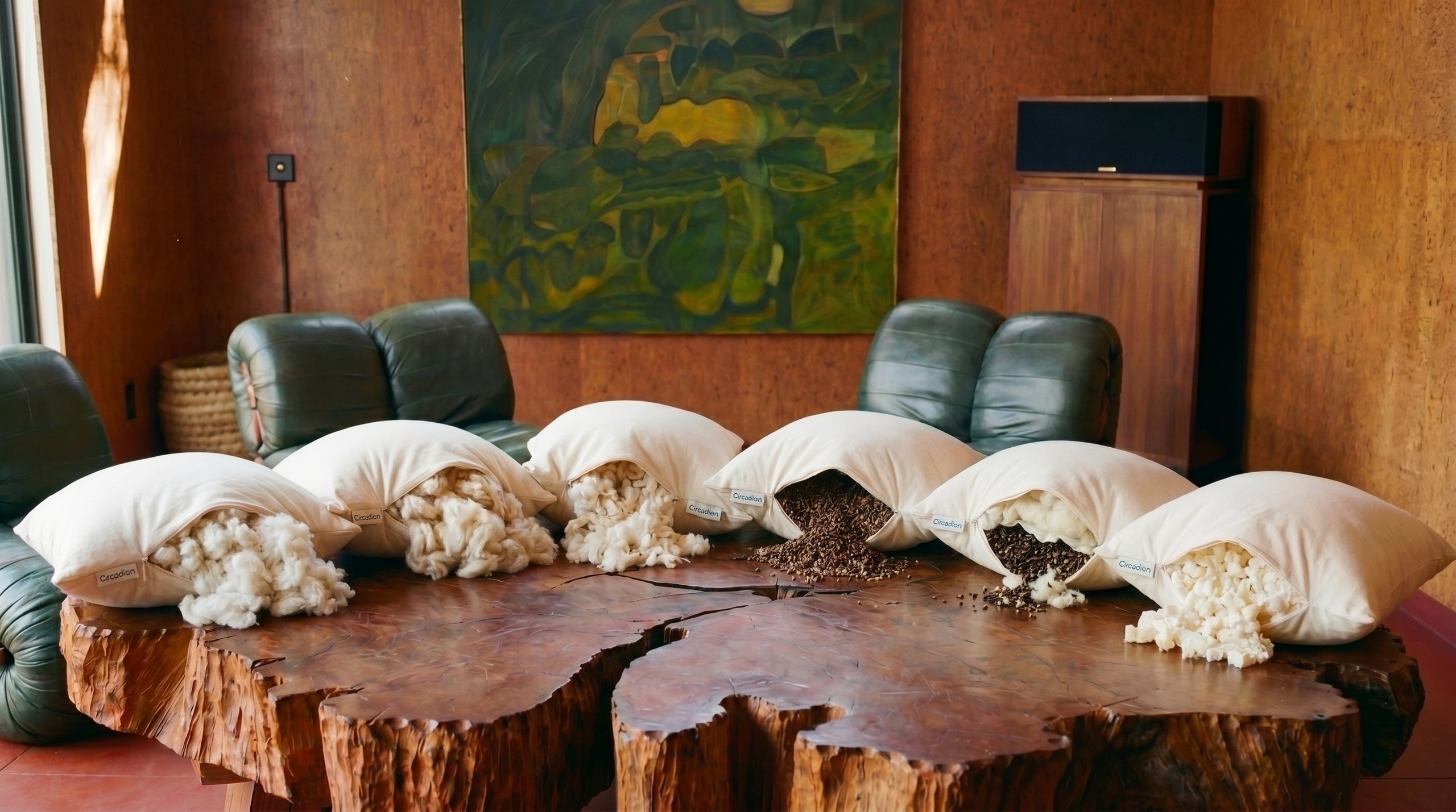 Six Circadian natural pillows in a row on a live-edge redwood table, fills spilling, warm mid-century room