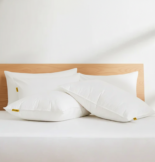 White organic kapok pillows on a bed with a wooden headboard