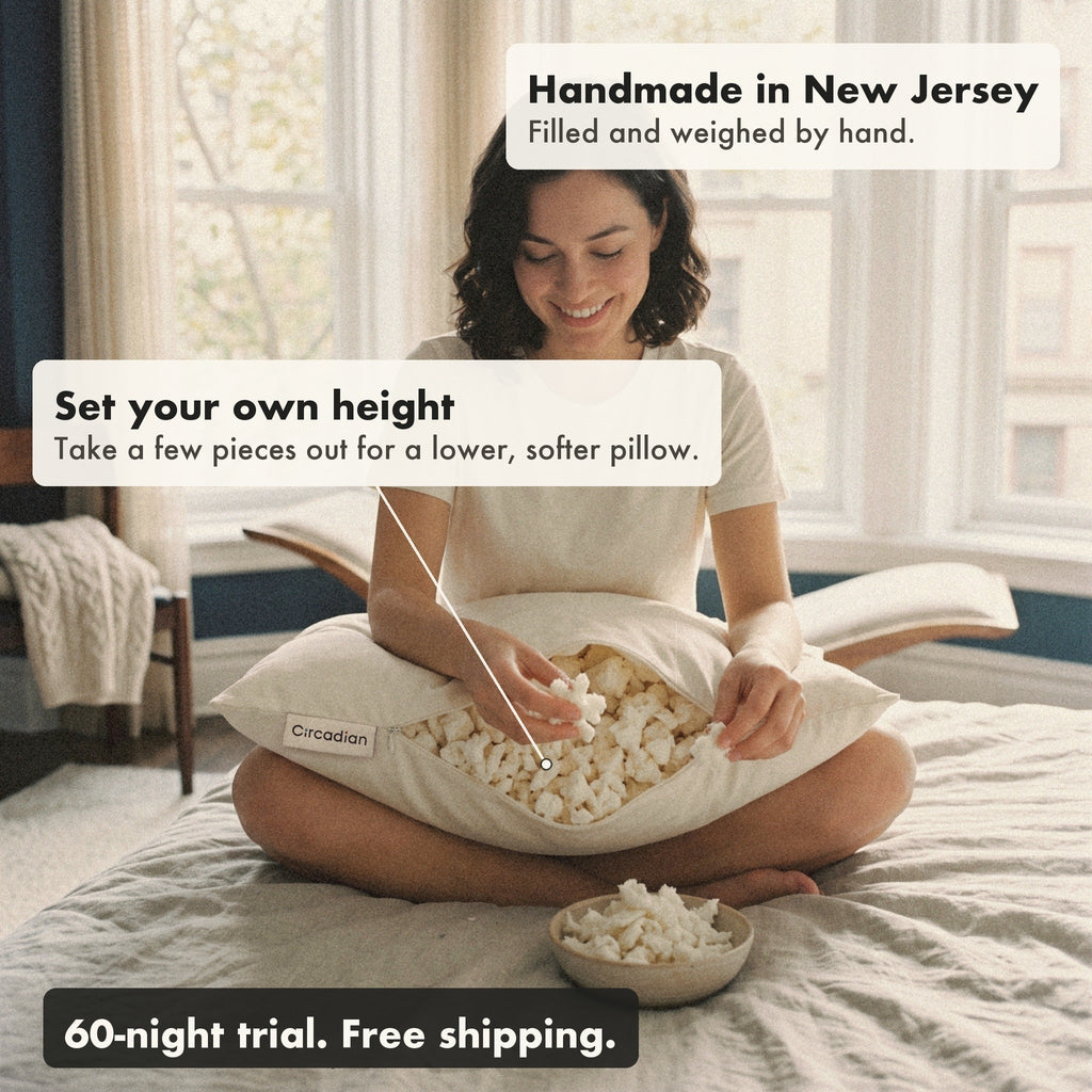 A smiling woman sits cross-legged on her bed taking a few pieces of latex out of the Tree-Tapped Latex Pillow into a bowl, with labels: set your own height, handmade in New Jersey, 60-night trial and free shipping.
