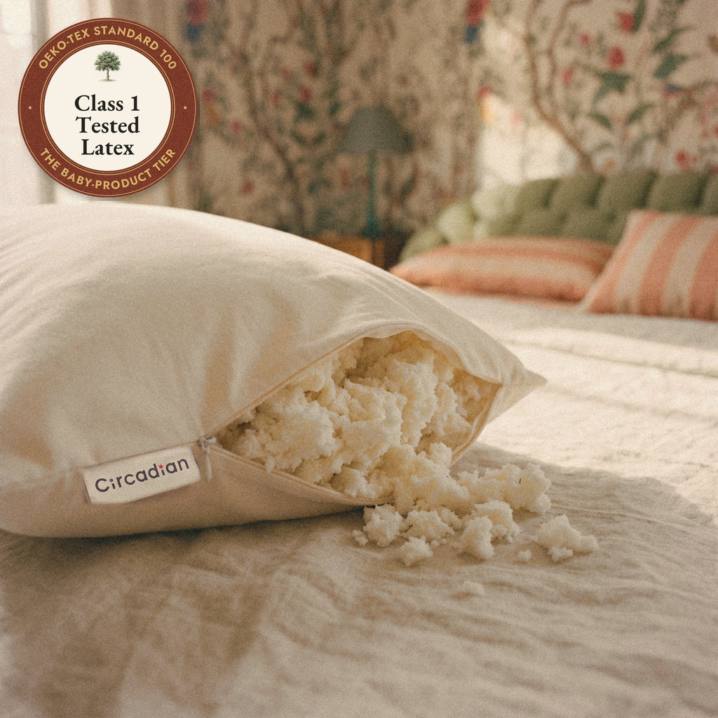 The woven Circadian label beside the open zipper of the Tree-Tapped Latex Pillow, soft pieces of latex spilling onto the bed, with a seal: Class 1 tested latex.