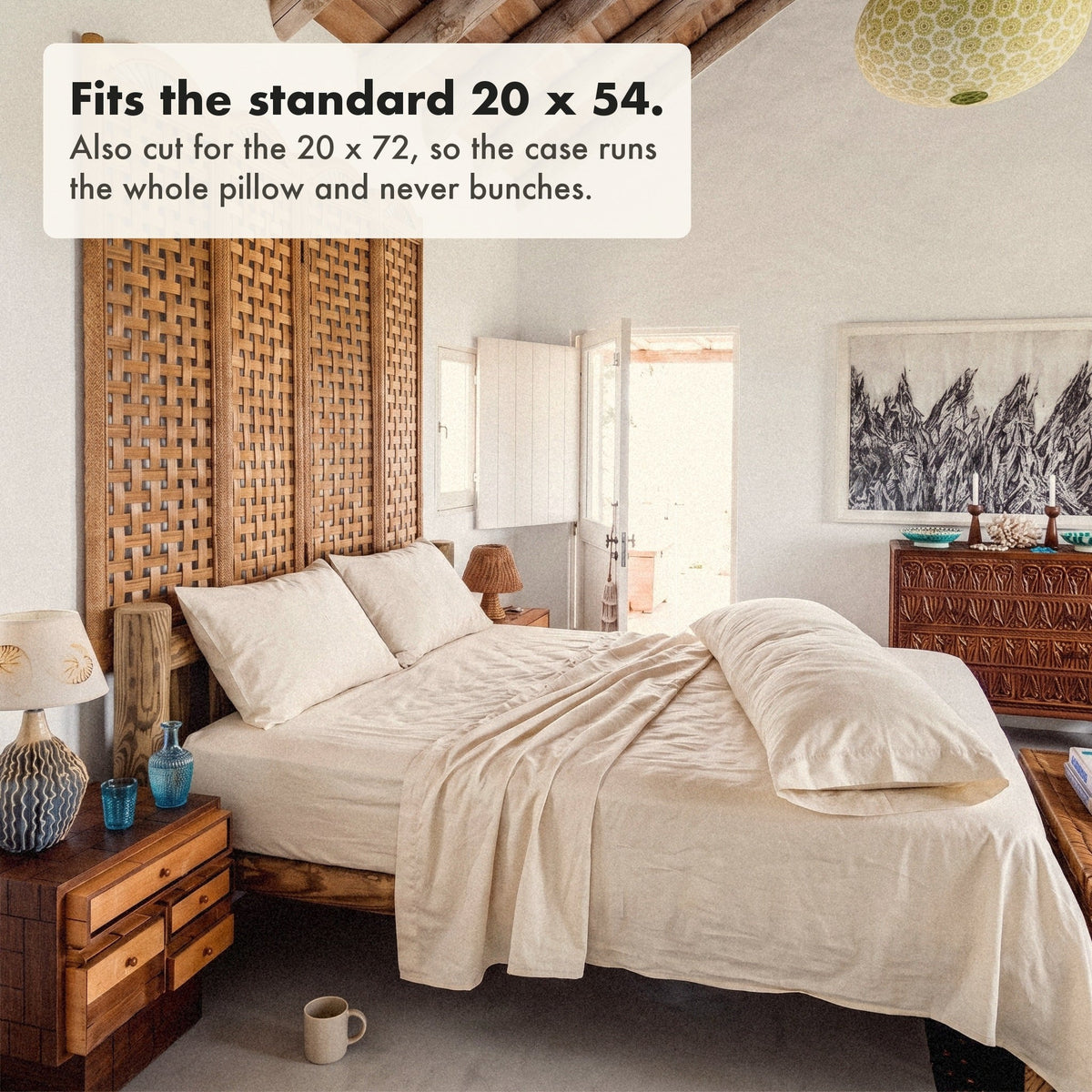 A body pillow in its organic cotton sateen case lying along the bed, labelled: fits the standard 20 x 54, also cut for the 20 x 72, so the case runs the whole pillow and never bunches.
