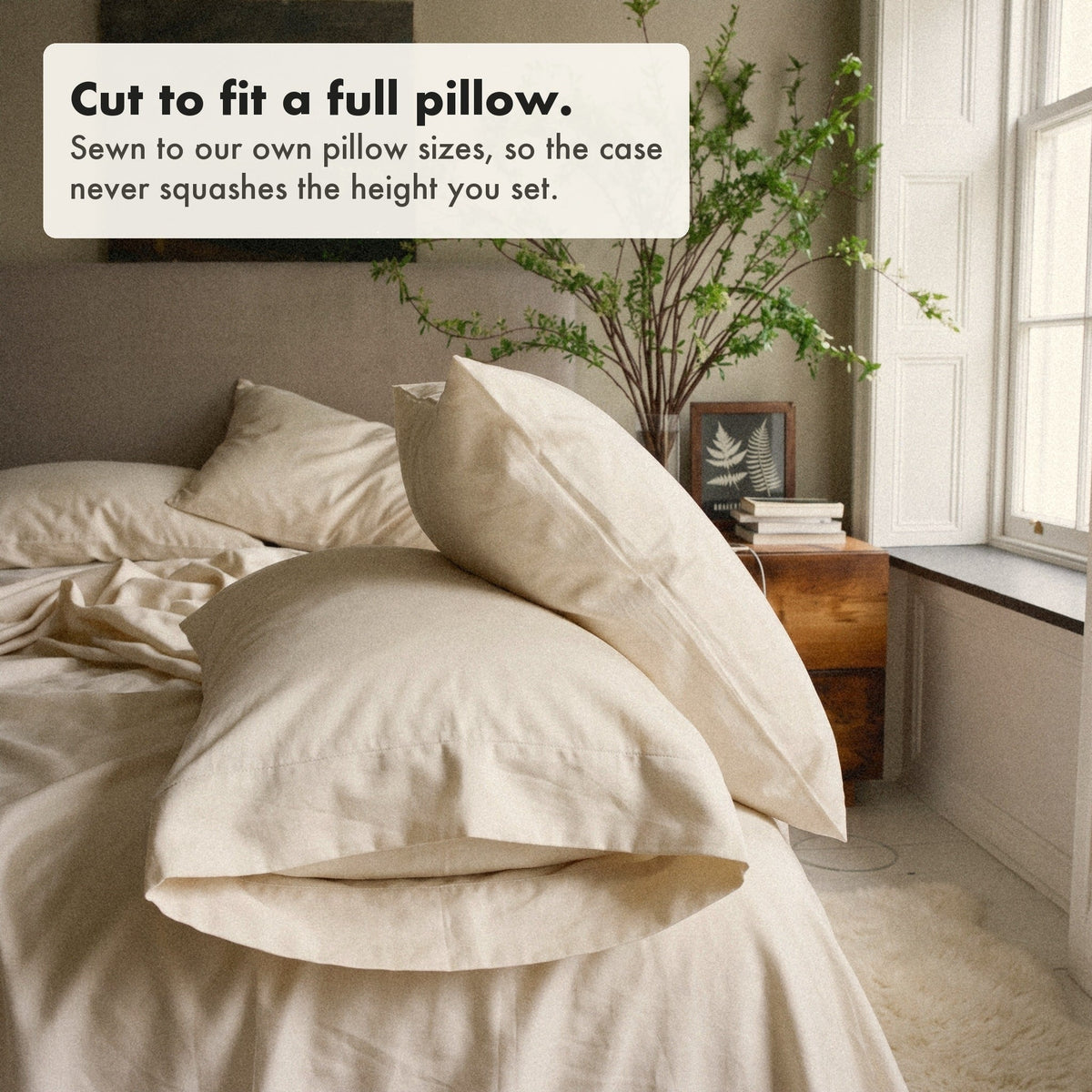 The open end of a slip-on organic cotton sateen pillowcase on the bed, labelled: cut to fit a full pillow, sewn to our own pillow sizes so the case never squashes the height you set.