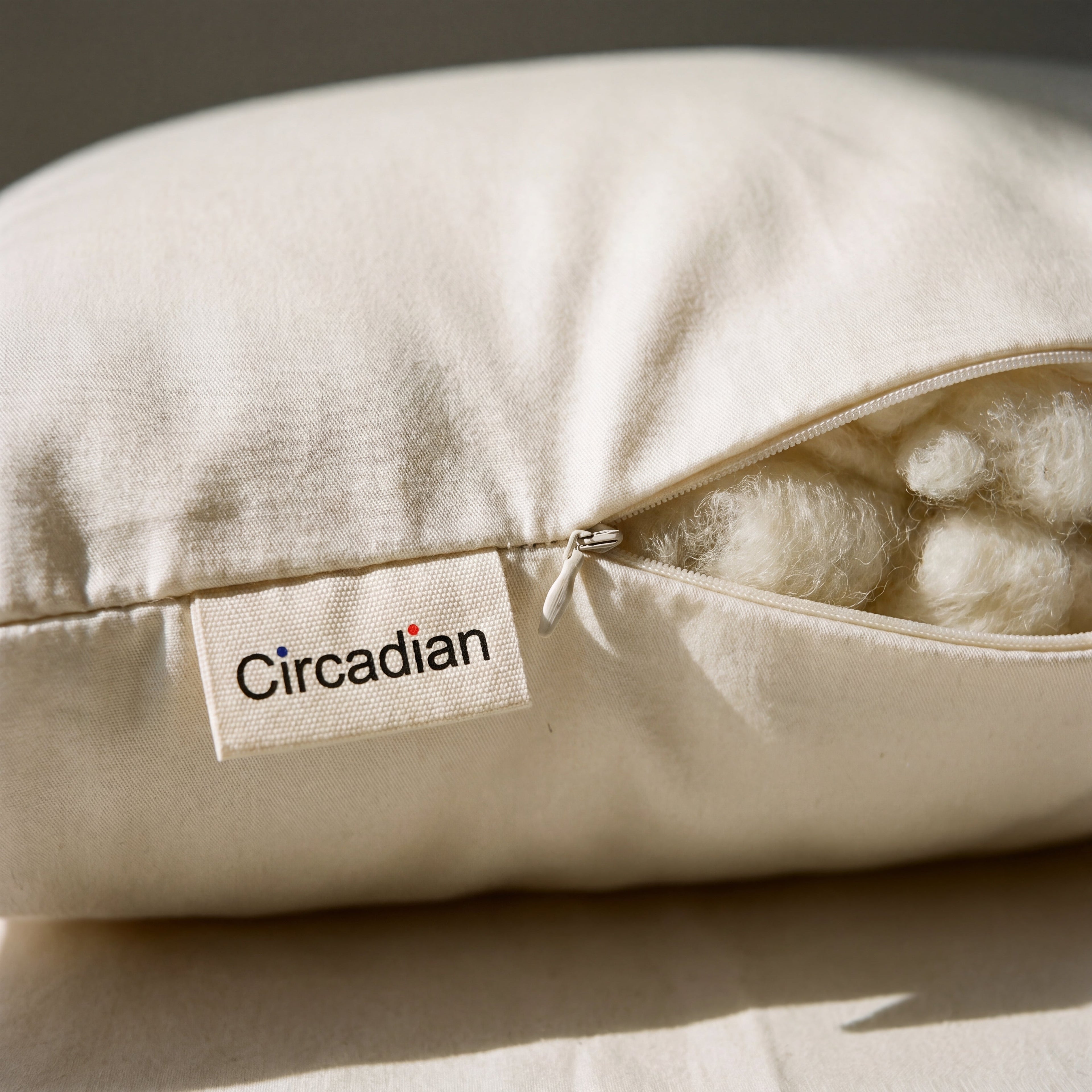 Concealed zipper and woven Circadian tag detail on the Organic Wool Pillow's GOTS-certified sateen cover