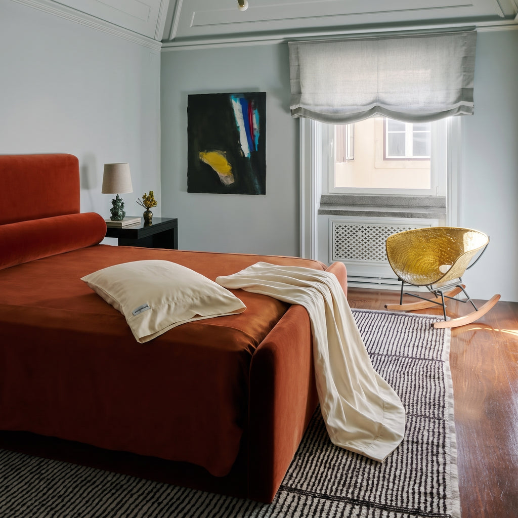 A pair of organic cotton pillowcases folded and draped on a daybed