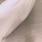 Hands open the zipper of the Organic Wool Pillow and press into the folded wool blanket inside.