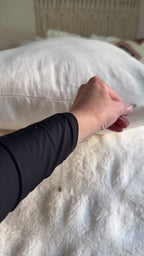 A woman unzips her King kapok pillow, takes out a bag of kapok to set her height, then lies down on it.