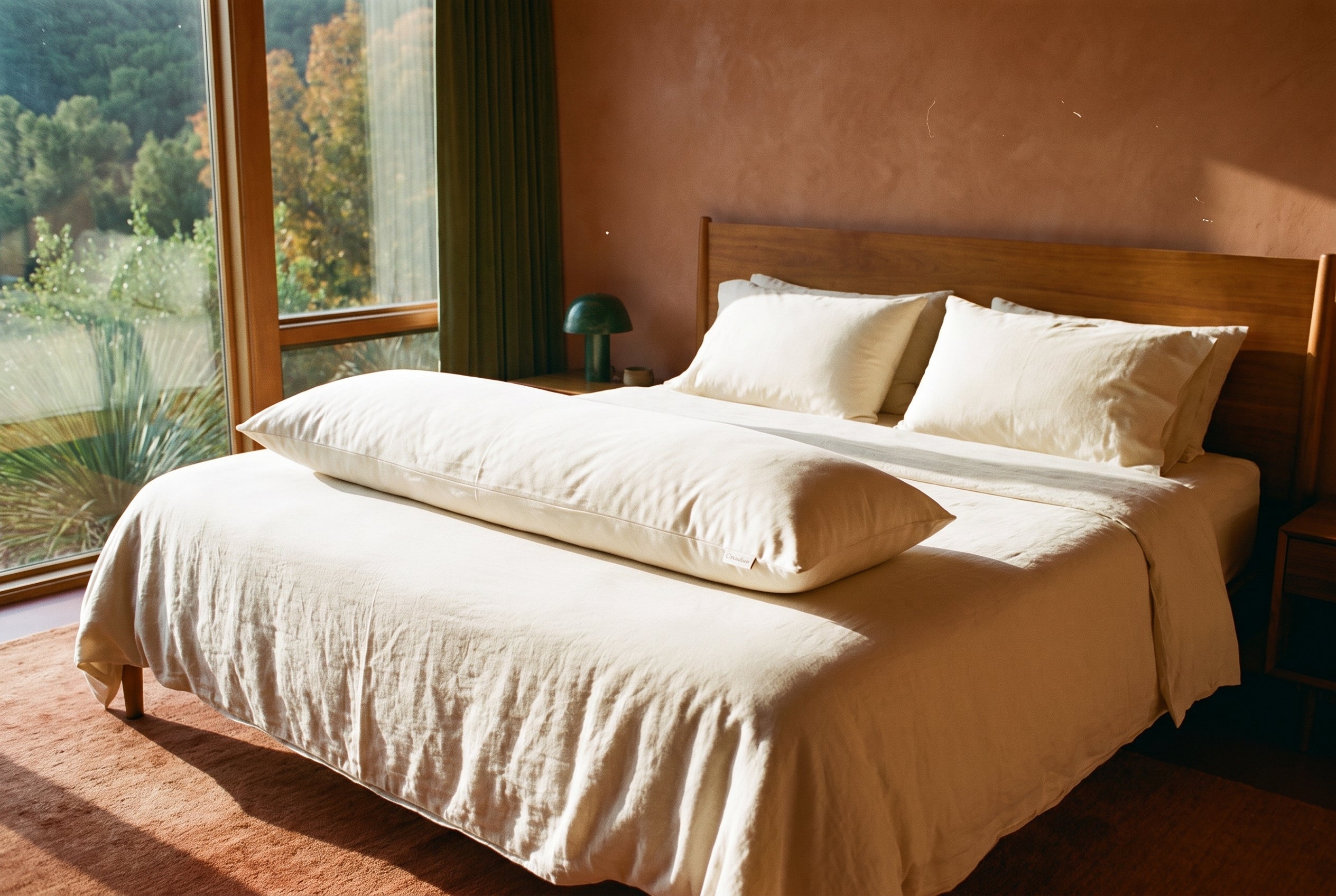 Circadian Body Pillow styled on a made bed in a warm terracotta bedroom with a canyon view.
