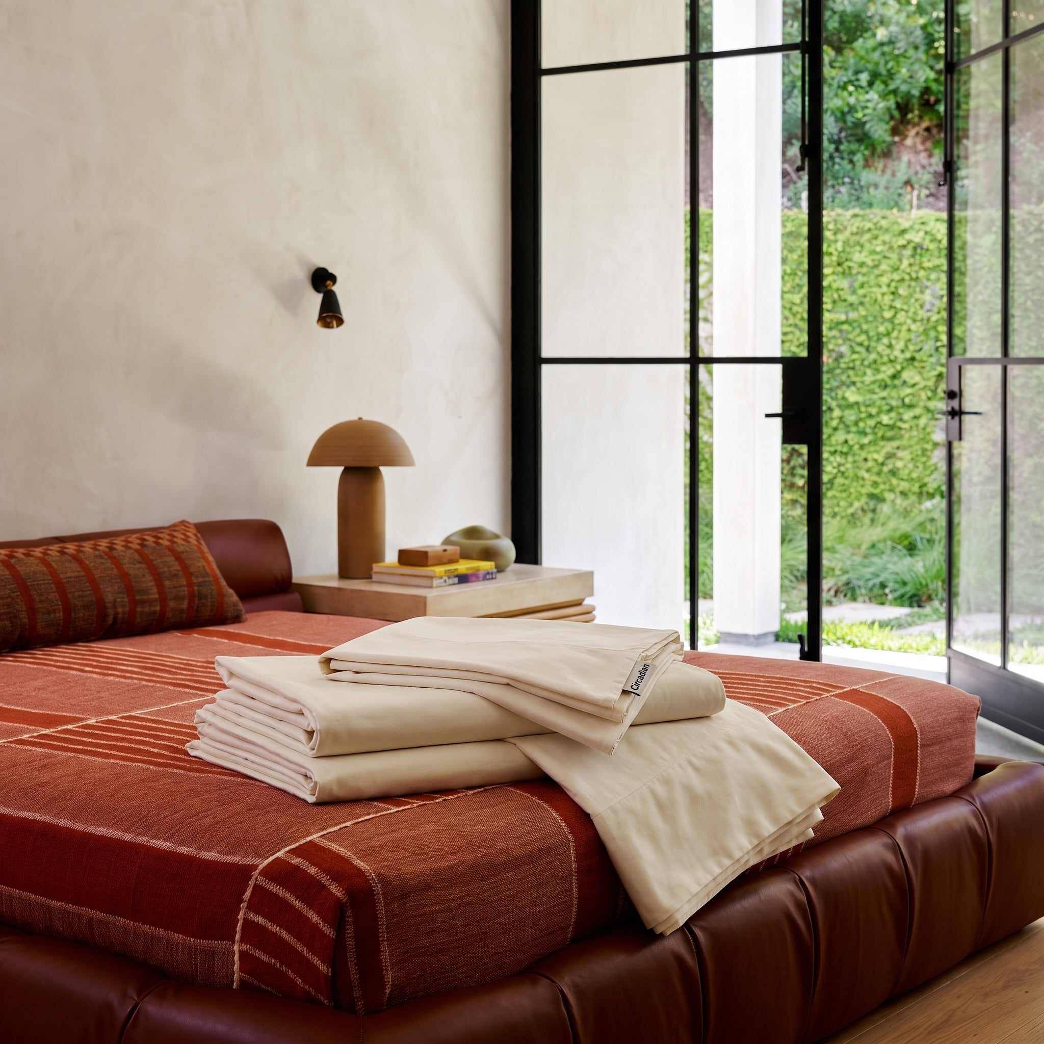 Folded organic cotton sheets and pillowcases stacked on a bed