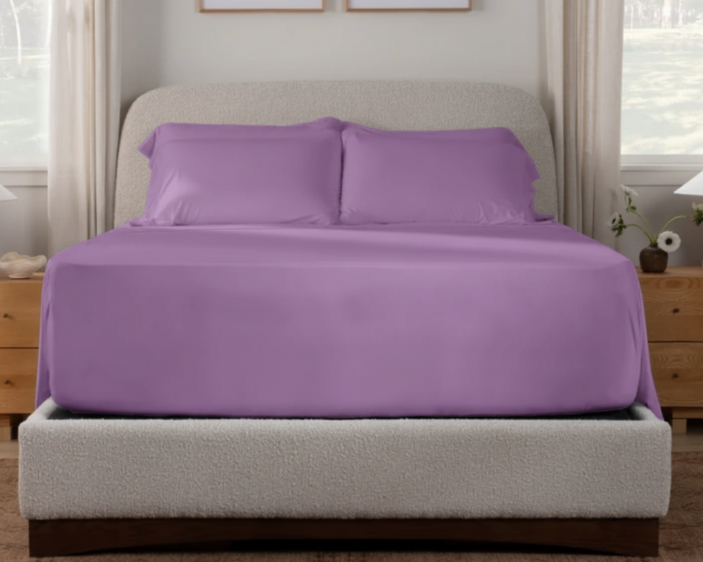 Purple bedspread and pillows on a bed in a bedroom setting.
