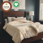 Morning sun on a dark wood bed. The Circadian Organic Wool Comforter, a hand-tufted duvet insert, lies thrown back, with the Handmade in the USA seal and the label of GOTS, the Global Organic Textile Standard (Organic, certified by OTCO, GOTS-10229).