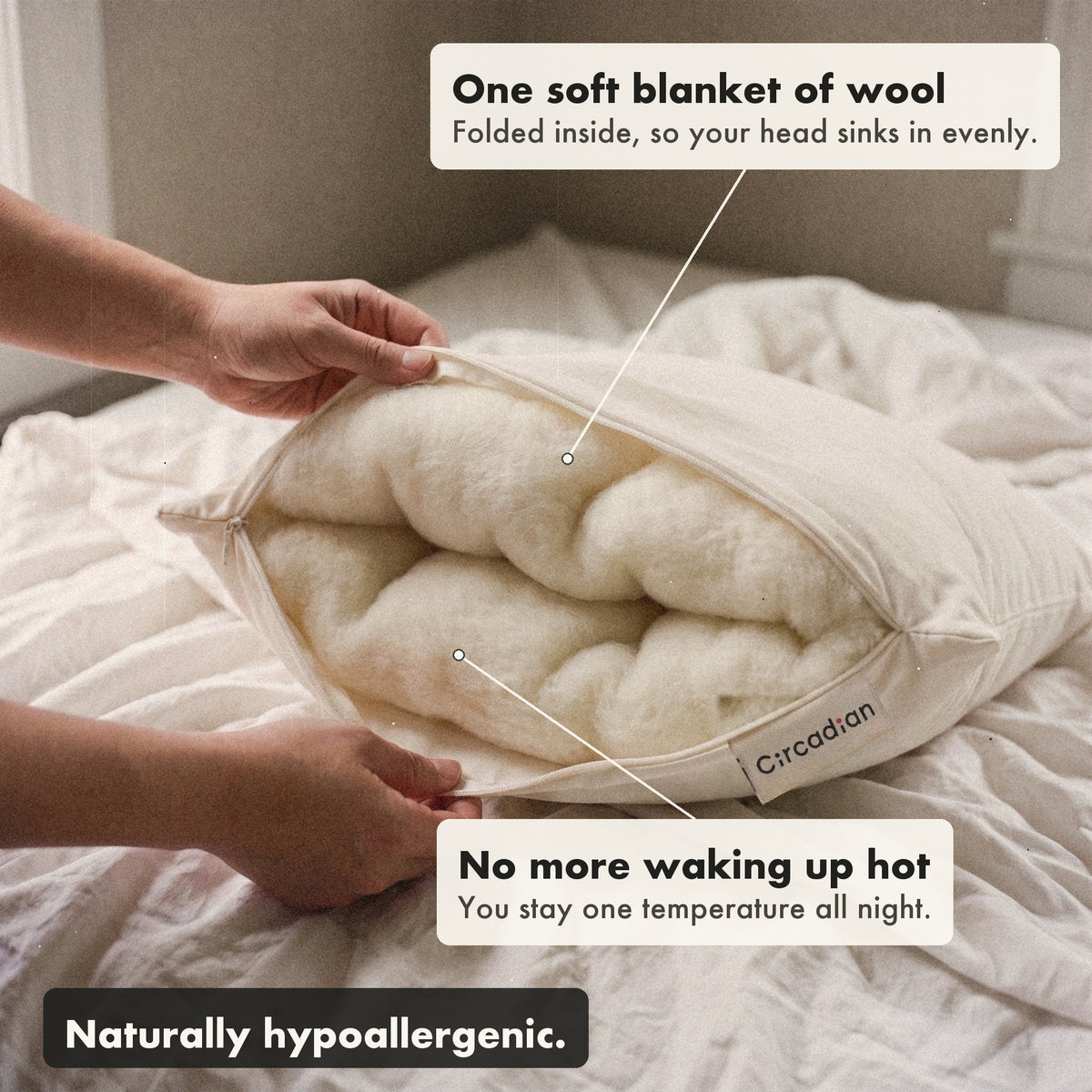 Hands open the zipper of the Organic Wool Pillow to show one soft blanket of wool folded inside, with labels: folded inside so your head sinks in evenly, no more waking up hot, naturally hypoallergenic.
